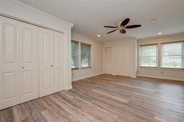 unfurnished bedroom with ceiling fan, ornamental molding, light hardwood / wood-style floors, and multiple windows