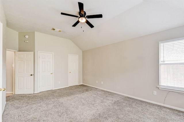 unfurnished bedroom with ceiling fan, lofted ceiling, and carpet