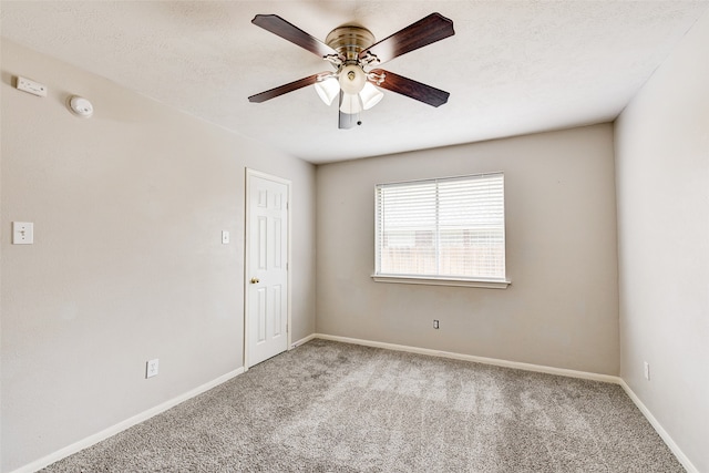 carpeted spare room featuring a textured ceiling and ceiling fan