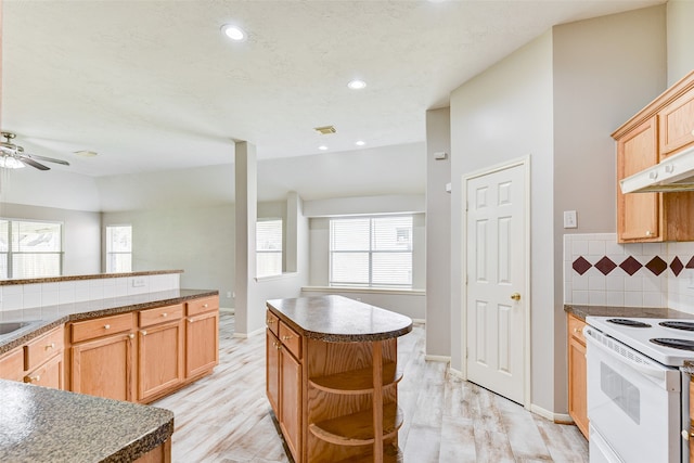 kitchen featuring decorative backsplash, a center island, light hardwood / wood-style flooring, ceiling fan, and electric range