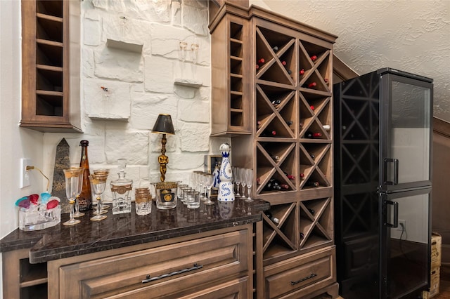 wine room featuring a textured wall and a dry bar