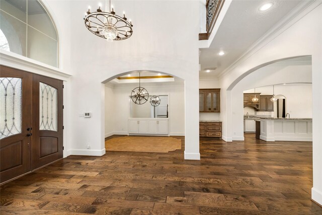 entrance foyer featuring sink, crown molding, dark hardwood / wood-style floors, french doors, and a chandelier