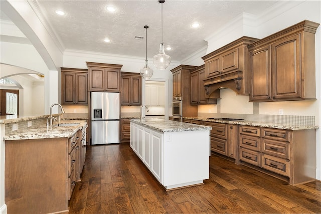 kitchen with arched walkways, stainless steel appliances, dark wood-type flooring, a sink, and a center island with sink