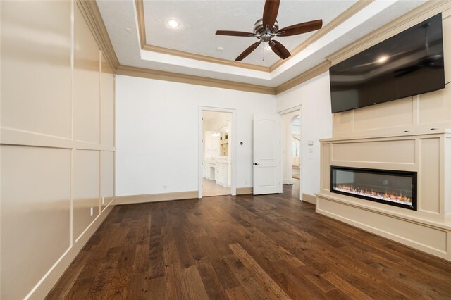 unfurnished living room featuring a raised ceiling, crown molding, dark wood-type flooring, and ceiling fan