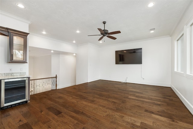 unfurnished living room with dark wood-style floors, wine cooler, a textured ceiling, and crown molding