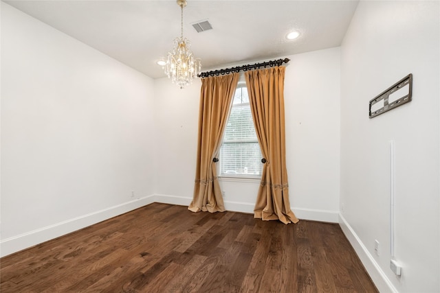 spare room featuring a notable chandelier and dark hardwood / wood-style flooring