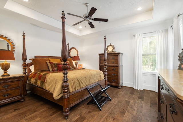 bedroom with a raised ceiling, dark wood-type flooring, and recessed lighting