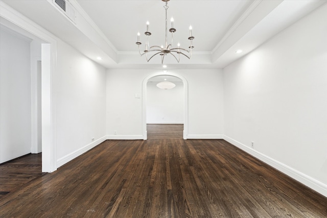 spare room featuring an inviting chandelier, a raised ceiling, dark hardwood / wood-style floors, and ornamental molding