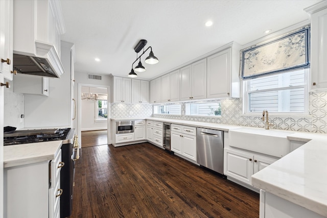 kitchen with premium range hood, decorative light fixtures, dark wood-type flooring, white cabinetry, and stainless steel appliances