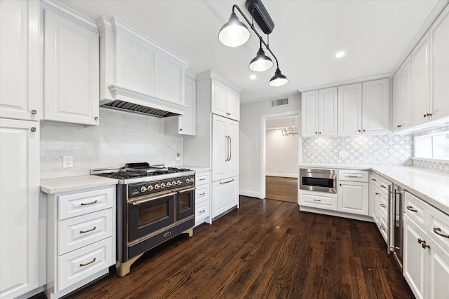 kitchen featuring pendant lighting, dark wood-type flooring, white cabinetry, appliances with stainless steel finishes, and decorative backsplash