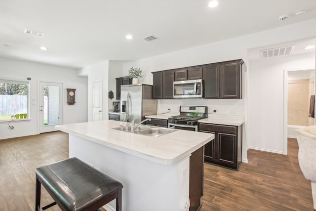 kitchen with a breakfast bar, sink, stainless steel appliances, a center island with sink, and dark hardwood / wood-style flooring