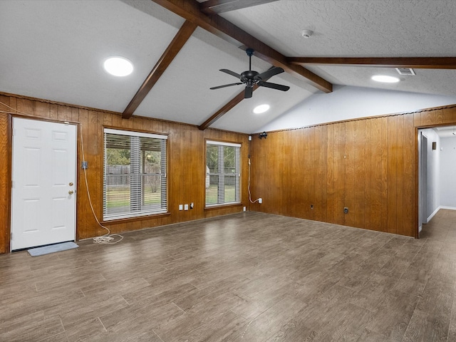 unfurnished living room featuring vaulted ceiling with beams, hardwood / wood-style flooring, and wooden walls