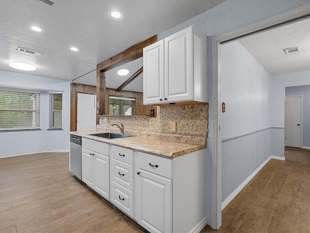 kitchen featuring dishwasher, white cabinets, sink, light hardwood / wood-style flooring, and beam ceiling