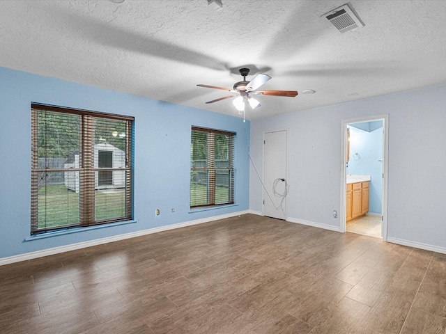 spare room with hardwood / wood-style floors, a textured ceiling, ceiling fan, and a healthy amount of sunlight