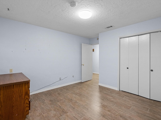 unfurnished bedroom with a closet, a textured ceiling, and light hardwood / wood-style flooring