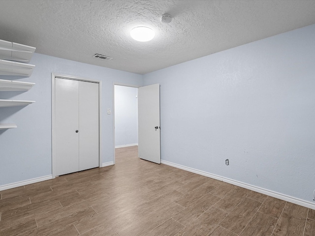 unfurnished bedroom featuring a closet, wood-type flooring, and a textured ceiling