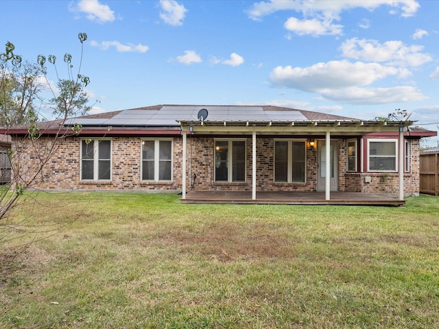 rear view of property with solar panels and a lawn