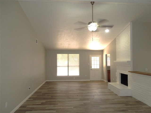 unfurnished living room featuring ceiling fan, a fireplace, hardwood / wood-style floors, and vaulted ceiling