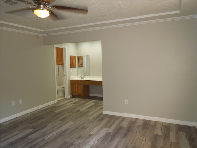 empty room featuring built in desk, crown molding, hardwood / wood-style floors, and ceiling fan