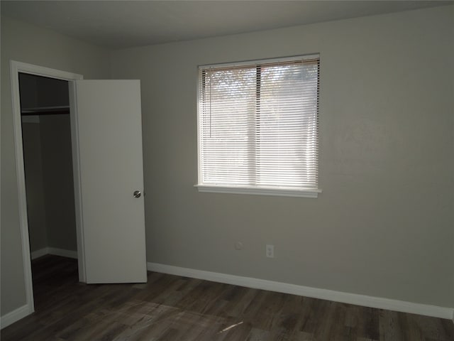 unfurnished bedroom featuring a closet, dark wood-type flooring, and multiple windows