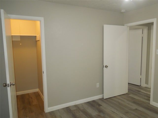 unfurnished bedroom featuring wood-type flooring, a closet, and a spacious closet