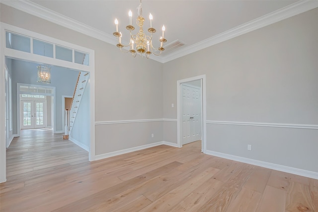 empty room with crown molding, light hardwood / wood-style flooring, a chandelier, and french doors