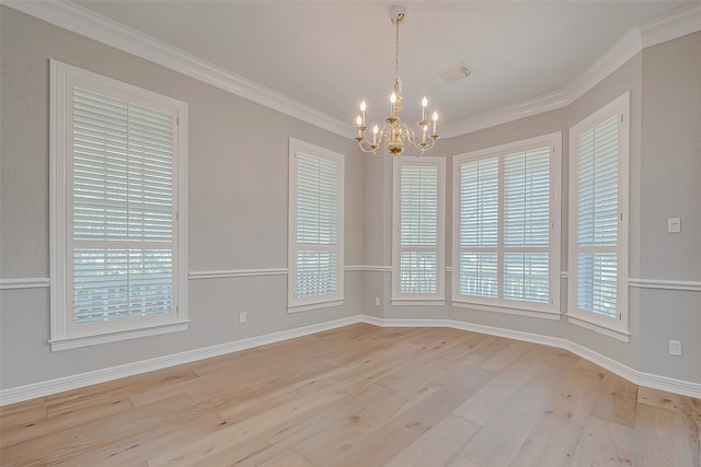 spare room featuring light wood-type flooring, plenty of natural light, crown molding, and a notable chandelier