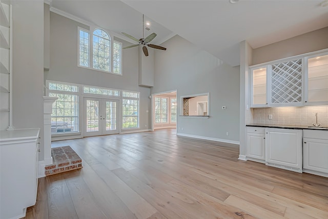 unfurnished living room featuring plenty of natural light, light hardwood / wood-style floors, a high ceiling, and ceiling fan