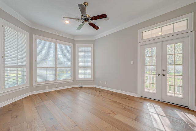 empty room with light hardwood / wood-style floors, ornamental molding, a wealth of natural light, and french doors