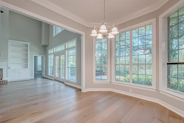 unfurnished dining area featuring crown molding, built in features, light hardwood / wood-style floors, and a notable chandelier