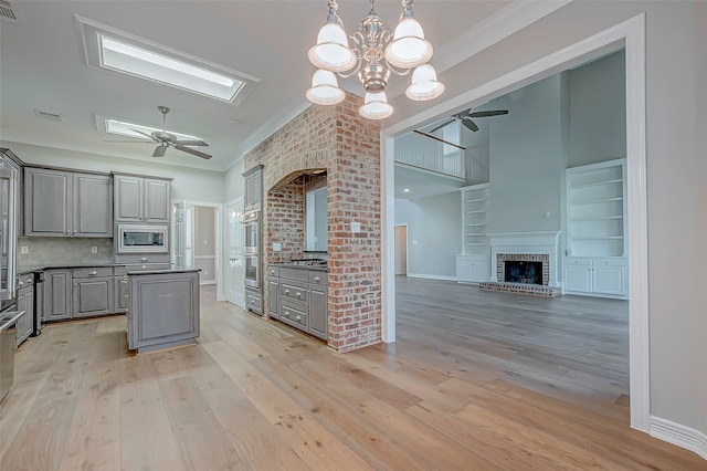 kitchen featuring gray cabinets, a fireplace, appliances with stainless steel finishes, and light hardwood / wood-style flooring