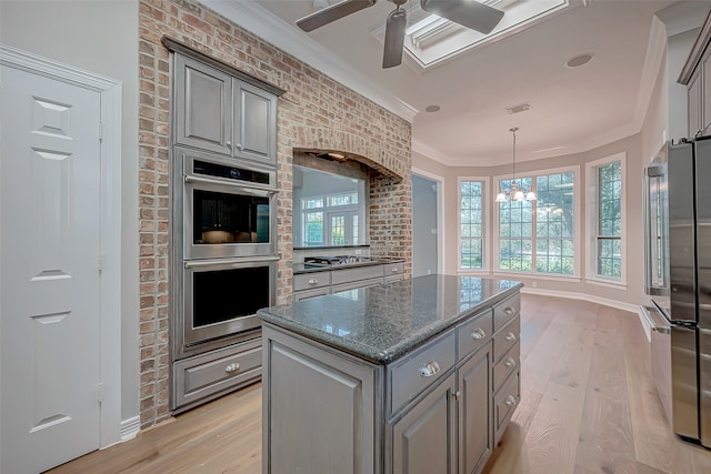 kitchen featuring appliances with stainless steel finishes, a center island, light hardwood / wood-style flooring, and plenty of natural light