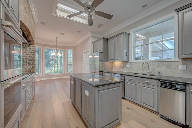 kitchen featuring a center island, sink, ornamental molding, appliances with stainless steel finishes, and light hardwood / wood-style floors