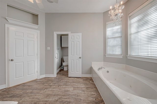 bathroom featuring a tub, a chandelier, wood-type flooring, and toilet