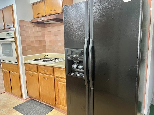 kitchen featuring white appliances, light tile patterned flooring, and tasteful backsplash