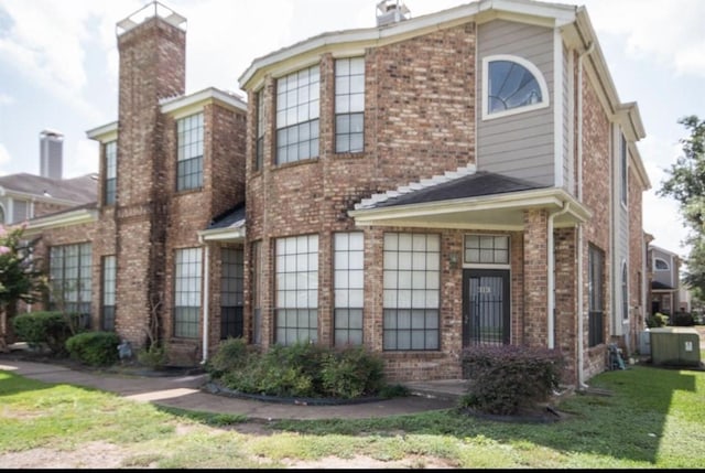 view of front facade with cooling unit and a front yard