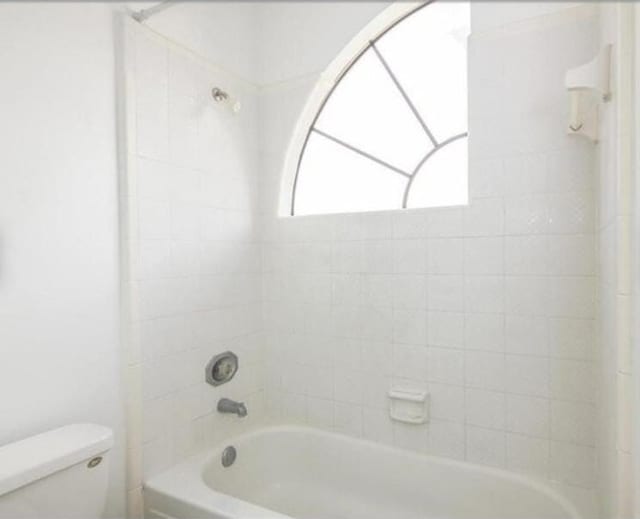 bathroom featuring toilet and tiled shower / bath