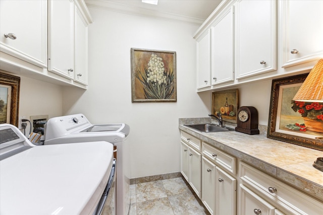 washroom featuring crown molding, washing machine and clothes dryer, cabinet space, a sink, and baseboards