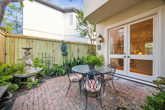 view of patio with outdoor dining space, french doors, and fence