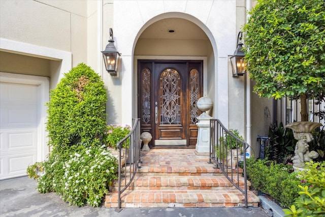 entrance to property featuring a garage and stucco siding