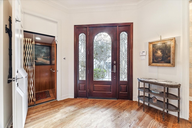 foyer entrance featuring ornamental molding, wood finished floors, and baseboards