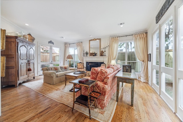 living room with ornamental molding, plenty of natural light, and light wood-type flooring