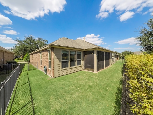 rear view of house featuring a lawn and a sunroom