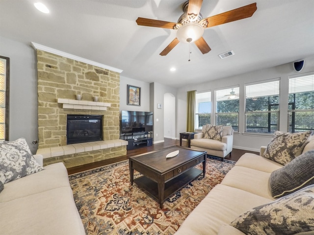 living room with wood-type flooring, ceiling fan, and a stone fireplace