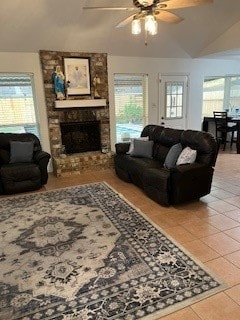 tiled living room featuring ceiling fan, a fireplace, and plenty of natural light