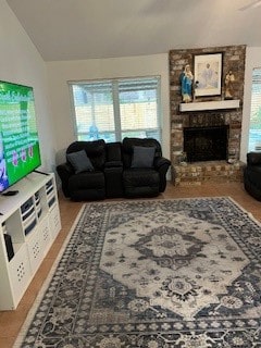 living room with a stone fireplace and vaulted ceiling