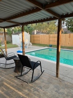 view of pool with a patio and a shed