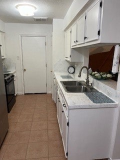 kitchen with light tile patterned floors, sink, electric range, and white cabinetry