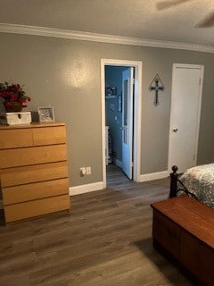 bedroom featuring ceiling fan, ensuite bath, dark wood-type flooring, and crown molding