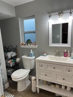 bathroom with vanity, toilet, and hardwood / wood-style flooring